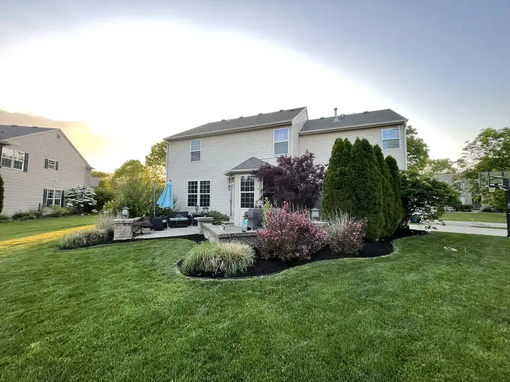 Backyard island bed with shrubs and perennials installed by J’s Design